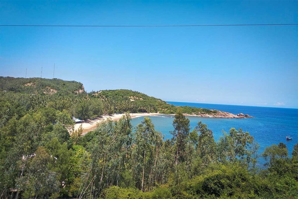 Rang Beach, Quy Nhon: hidden crescent cove framed by green hills and clear blue sea, few visitors.