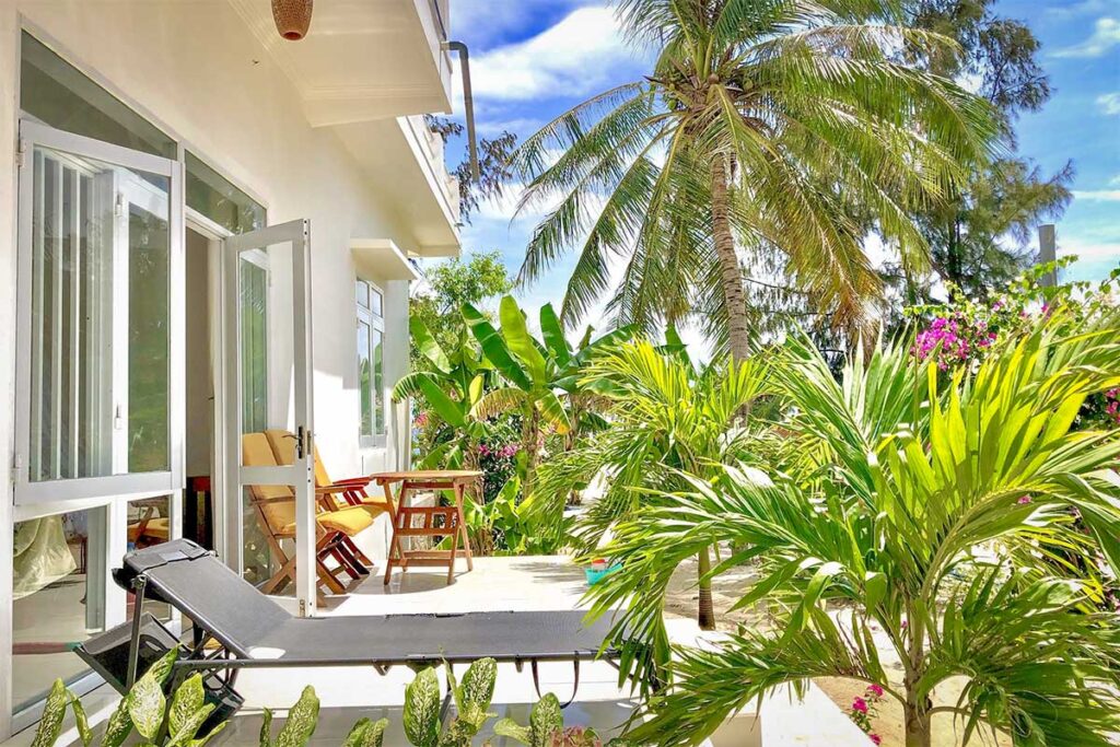 Robinson Beach Bungalow — simple beachfront rooms with a thatched dining hut under palm trees.