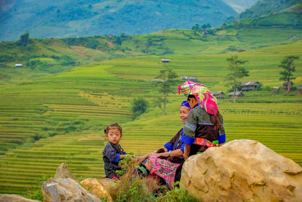 Sapa tours – Local Vietnam | ethnic minority women and child sitting on rocks overlooking rice terraces in Sapa, northern Vietnam
