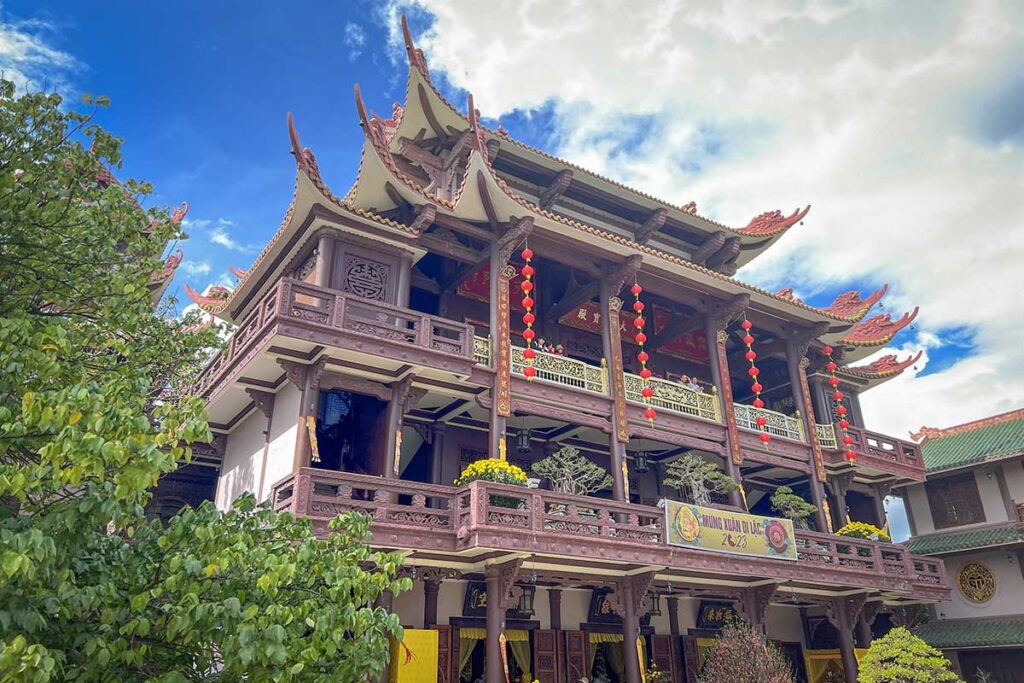 Main hall of Thien Hung Pagoda in Binh Dinh with traditional curved roofs and red lanterns during daylight.