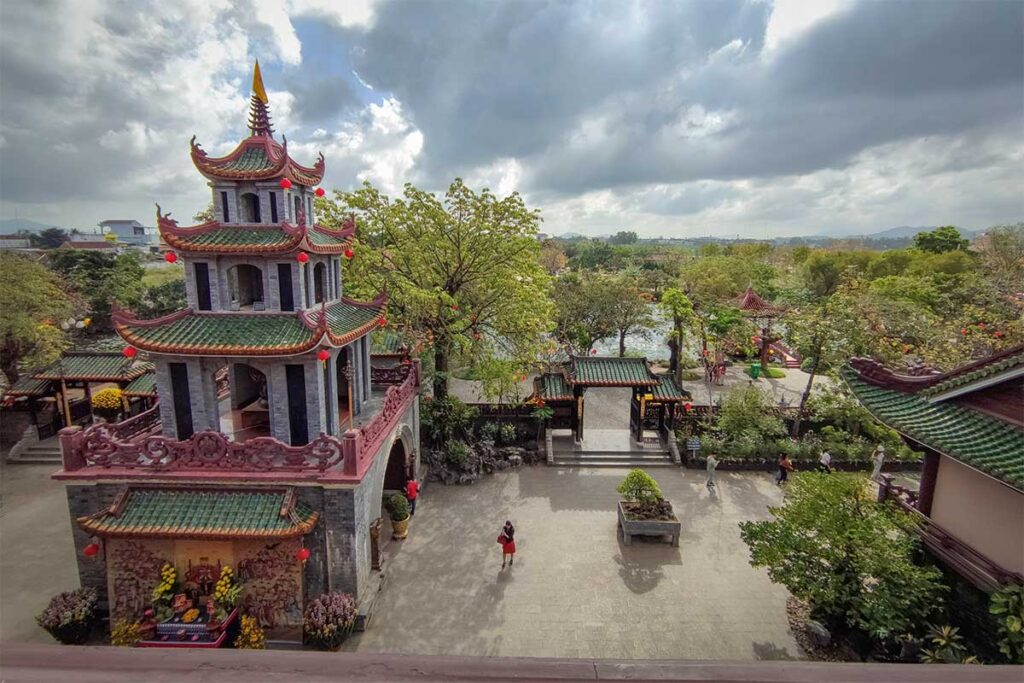 Bell tower and courtyard of Thien Hung Pagoda in Binh Dinh seen from above, with gardens and pathways beyond.