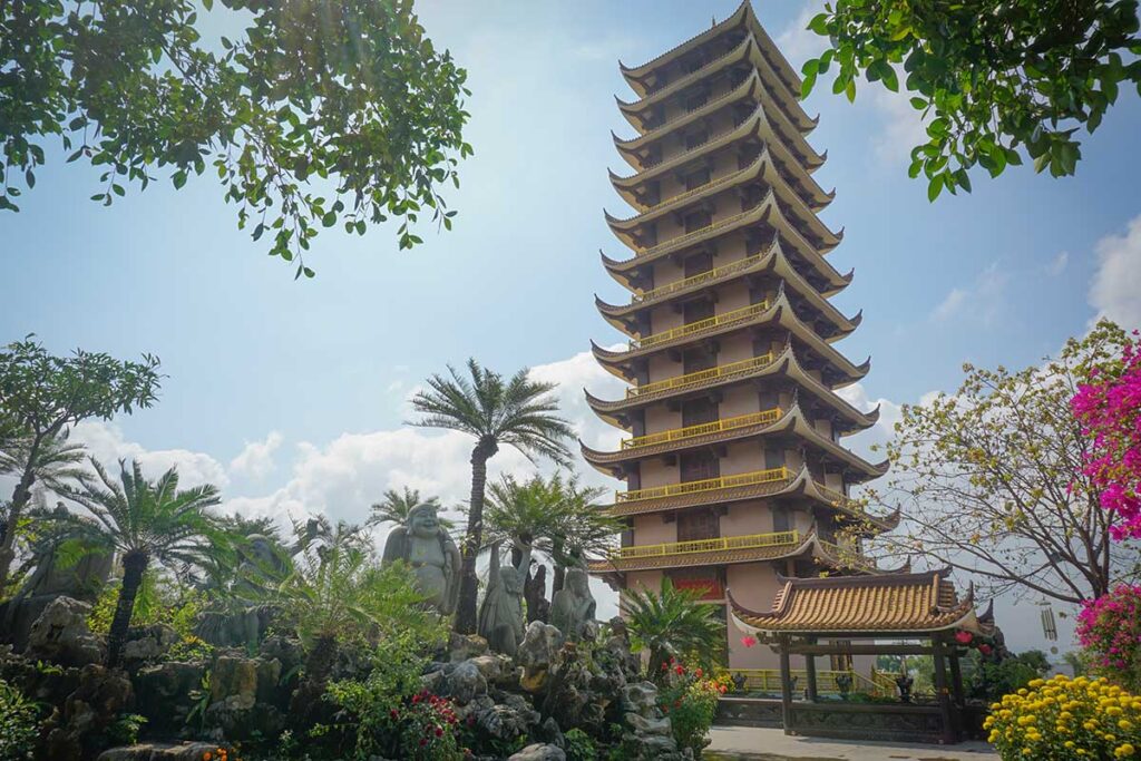 Tall 12-story stupa at Thien Hung Pagoda in Binh Dinh with statues and landscaped gardens in the foreground.