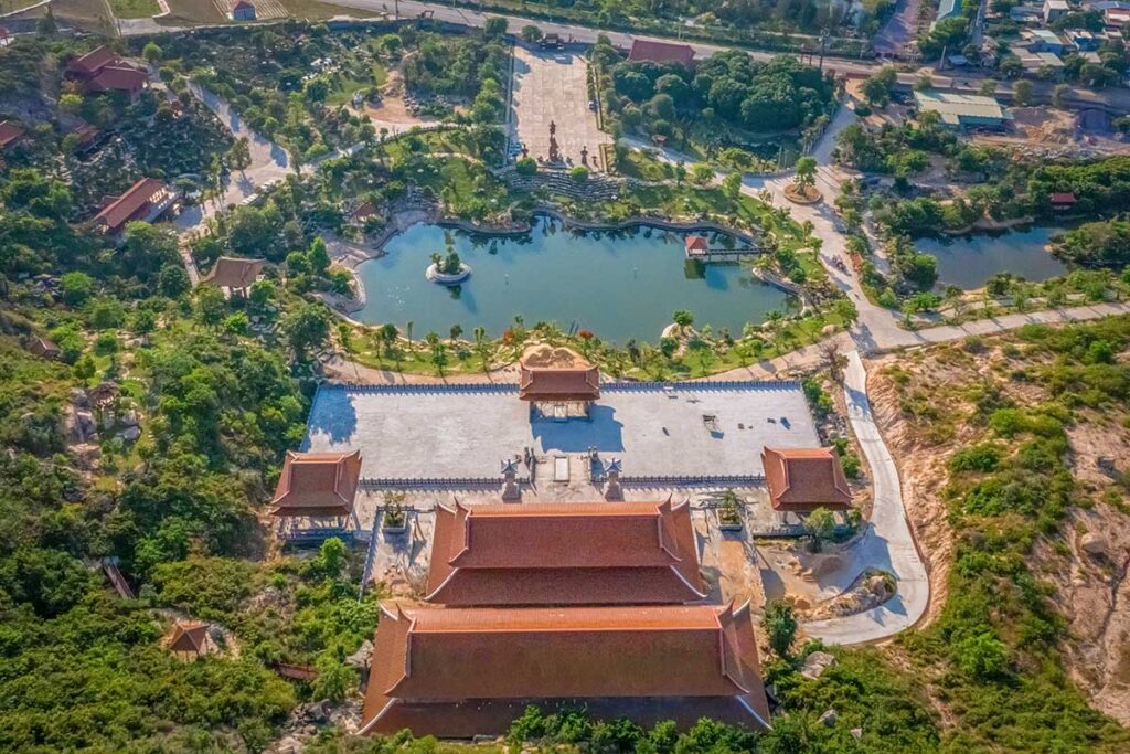 Aerial view of Thien Hung Pagoda complex in Binh Dinh with large courtyard, lotus lake, and surrounding greenery.