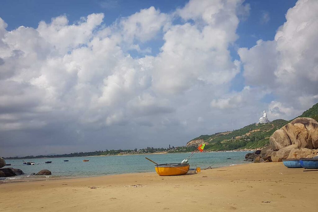 Trung Luong Beach with basket boats and the giant Buddha of Linh Phong (Ong Nui) Pagoda on the hill.