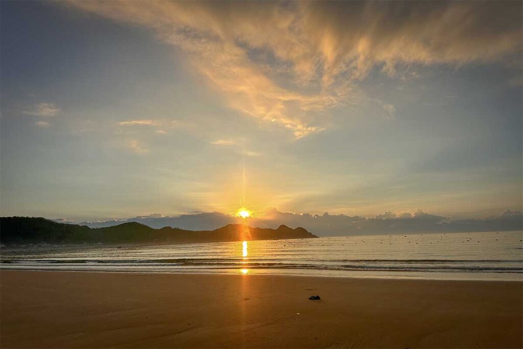 Sunrise over Tu Nham Beach, Phu Yen, reflecting on calm waves and empty golden sand.