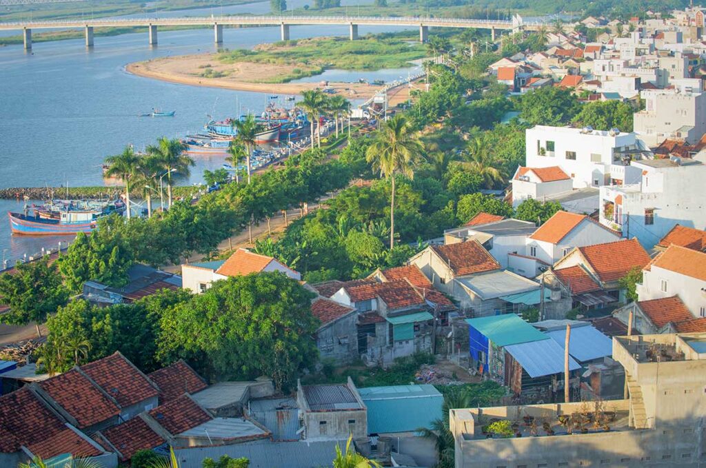 Rooftops of Tuy Hoa city with the Da Rang River winding past and the coastline visible in the distance.