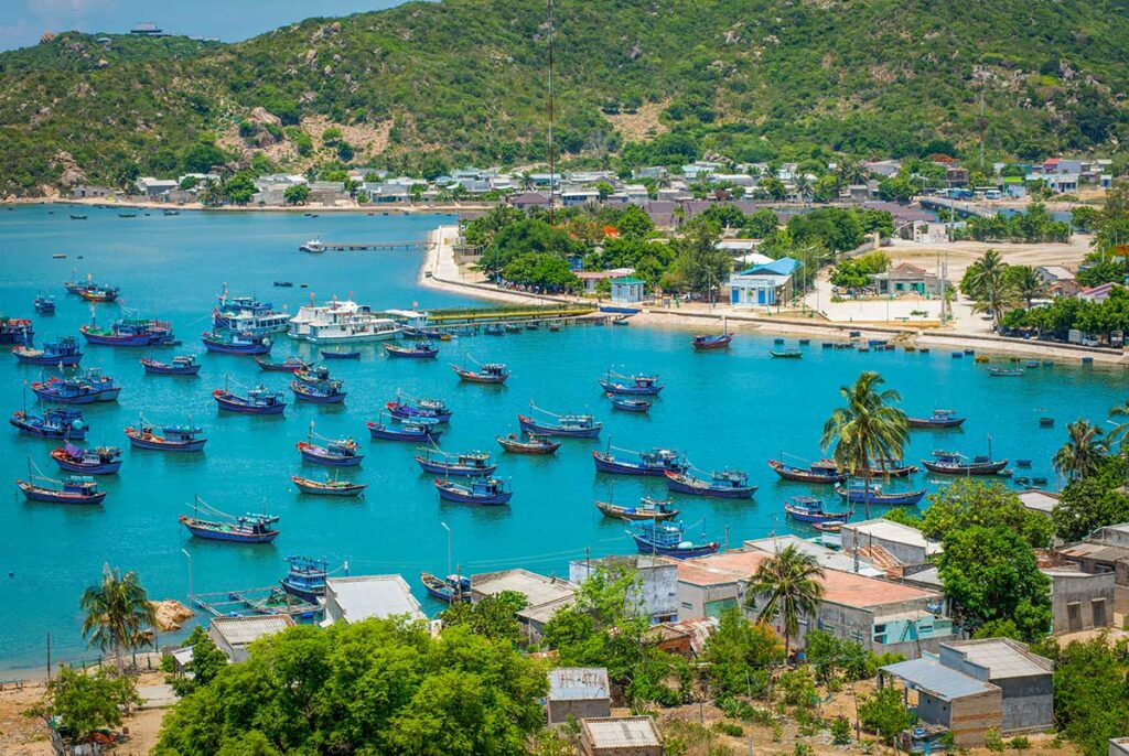 Fishing village scene at Vinh Hy Bay – Traditional houses and boats clustered around the harbor, showing the daily life of a small Vietnamese fishing community.