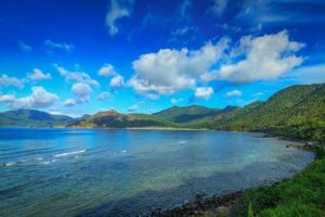 Con Son Island tours showcasing a peaceful coastline surrounded by green mountains and turquoise water