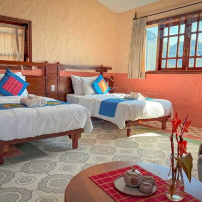 Double bed in the Connecting Family Room at Ha Giang Aya Lodge with large windows overlooking the mountains.