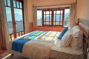 Double bed in the Connecting Family Room at Ha Giang Aya Lodge with large windows overlooking the mountains.