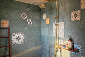 Shower area of the Connecting Family Room at Ha Giang Aya Lodge with patterned tiles and brass fixtures.