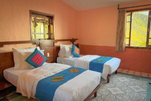 Twin-bed setup in the Deluxe Room at Ha Giang Aya Lodge with warm decor and hillside views.