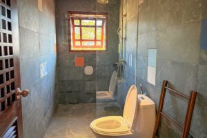 Bathroom of the Deluxe Room at Ha Giang Aya Lodge with walk-in shower and stone tile walls.