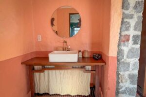 Handcrafted wooden vanity and warm terracotta interior in the Grand Suite bathroom at Ha Giang Aya Lodge.