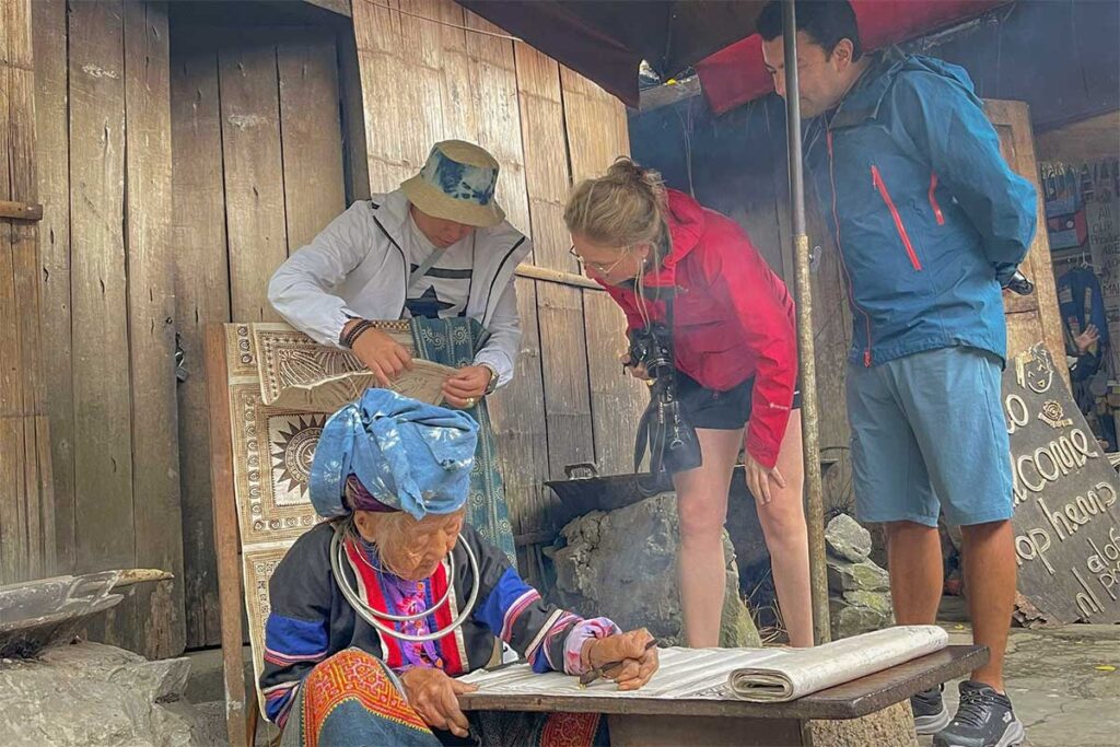 Travelers on a Local Vietnam tour learning traditional crafts from an ethnic minority woman in Ha Giang Province, reflecting the agency’s focus on authentic local connections.