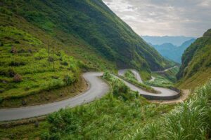 Scenic mountain road winding through lush green valleys in Ha Giang — a highlight of many Vietnam tours and Vietnam itineraries exploring the country’s remote northern region.