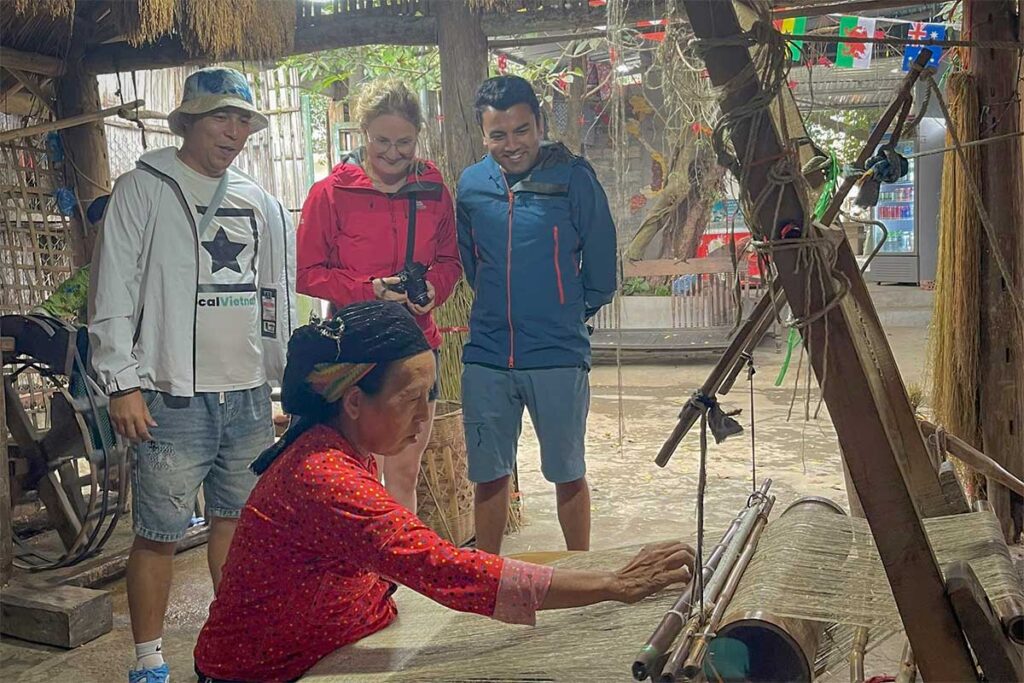 Local Vietnam guide with travelers visiting a traditional weaving village — authentic cultural stop often included when booking Vietnam car rental with driver for multi-day tours.