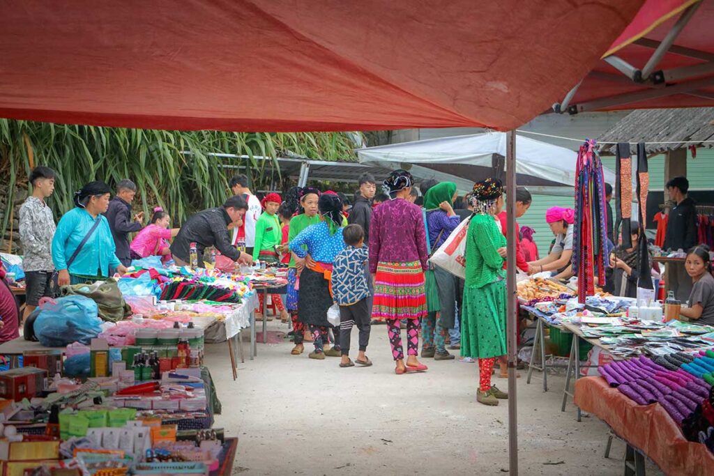 Colorful scene at Sung Trai Market in Ha Giang with ethnic minority vendors and traditional clothing.