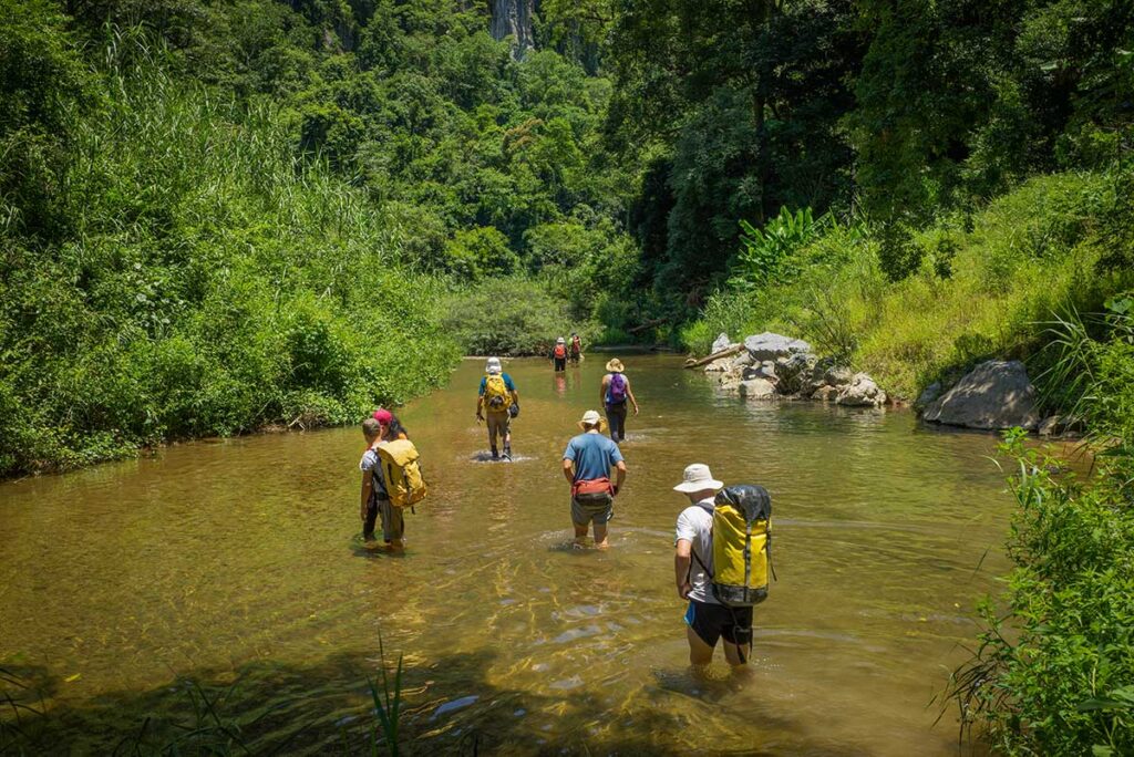 Travelers trekking through a river in Phong Nha-Ke Bang National Park, one of the adventure highlights of a Vietnam package tour.
