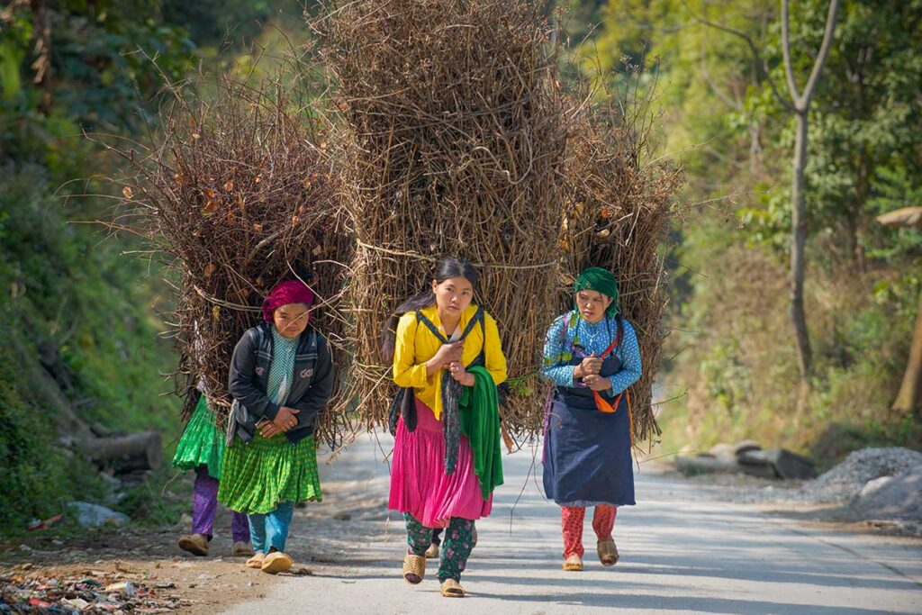 Ethnic women walking along a mountain road surrounded by limestone peaks on the Ha Giang Loop, a popular route for adventurous Vietnam tours.