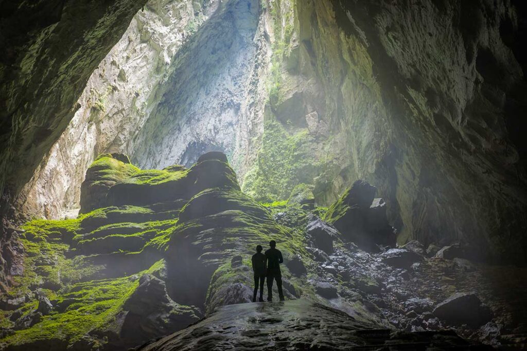 Explorers standing inside a giant cave in Phong Nha-Ke Bang National Park – an adventurous activity featured in Vietnam tours.