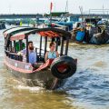 Tourists on a wooden boat exploring Cai Be Floating Market, Tien Giang Province, Vietnam
