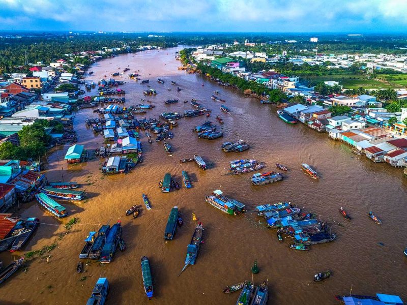 cai rang can tho city 1 Cai Rang Floating Market Aerial View: Aerial view of the bustling Cai Rang floating market on the Mekong River, with Can Tho city's skyline visible in the distance.