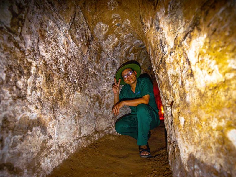 A local tour guide kneeling down inside the Cu Chi Tunnels, one of the best things to do in Vietnam.