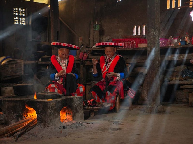 ethnic minority cao bang Two Red Dao ethnic minority woman inside a house cooking on an open fire in Cao Bang