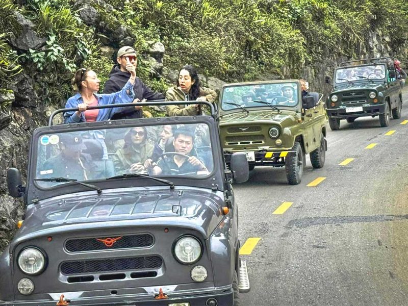 ha giang jeep tour 1 Tourists on an open jeep tour in Ha Giang standing and admiring the stunning mountain scenery.