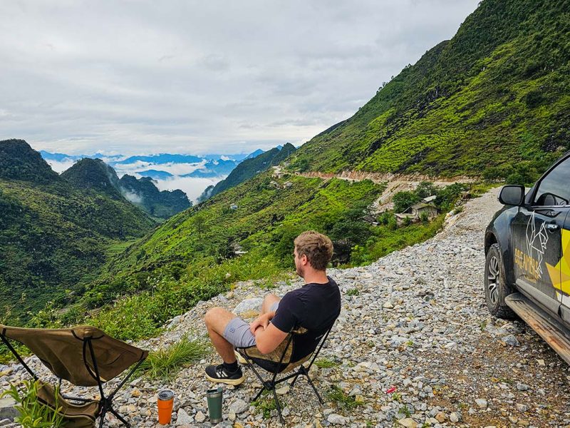 ha giang loop by car 2 Ha Giang Loop by car - a traveler sitting in front of a car watching the stunning mountain scenery of Ha Giang