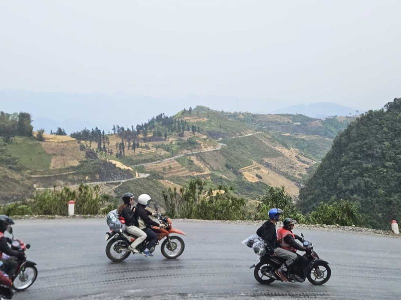 ha giang loop easy rider tour motorbike 7 Side view of three Easy Rider motorbikes with tourists on a winding Ha Giang mountain road