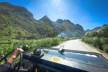 View from inside a military jeep driving along a scenic mountain road in Ha Giang