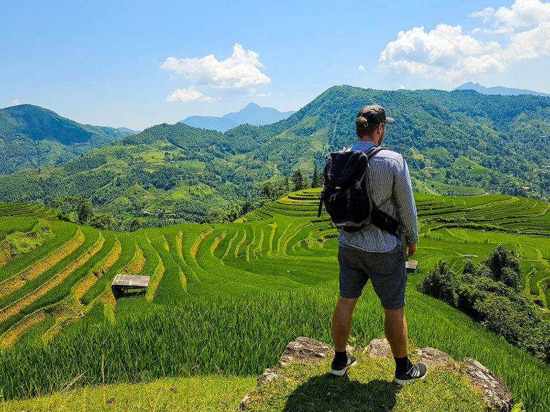 A tourist is enjoying the view over terraced rice fields during a trekking in Hoang Su Phi