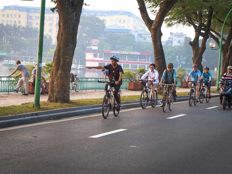 Tourists and guide biking along West Lake during a Hanoi cycling tour
