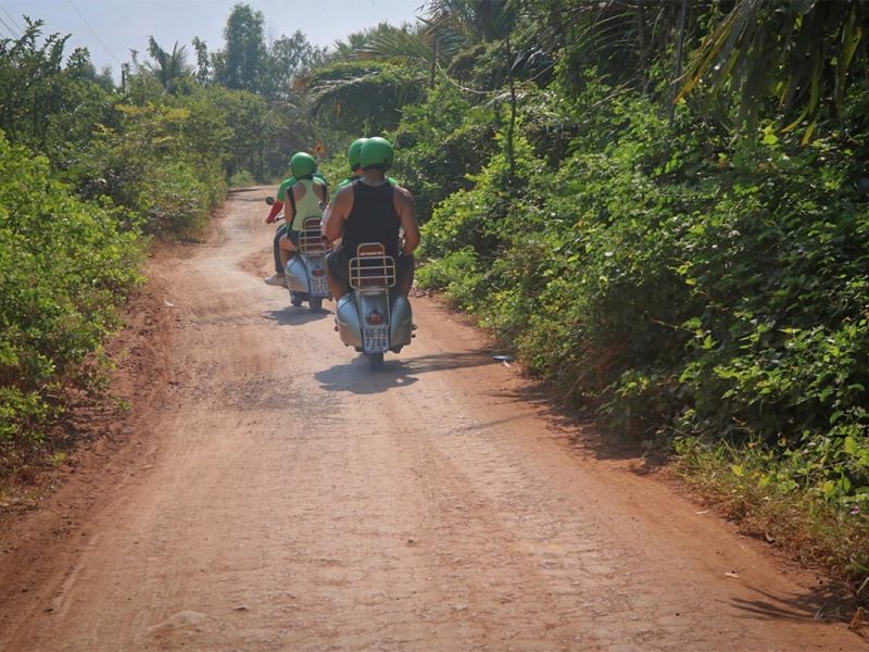 hoi an motorbike tour by vespa 11 Hoi An Vespa tour driving down a narrow red-dirt trail surrounded by tropical greenery