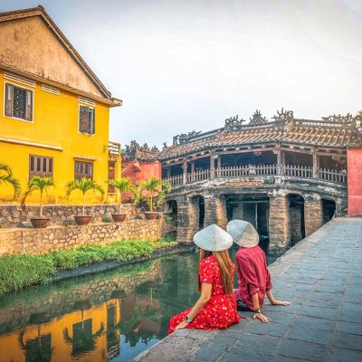 A couple sitting next to the Japanese Bridge in Hoi An for a romantic time in Vietnam