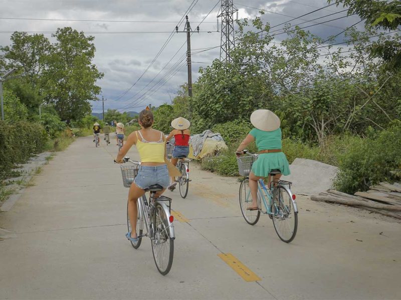 hue countryside cycling tour 2 Travelers cycling along rural lanes surrounded by greenery during a Hue countryside cycling tour.