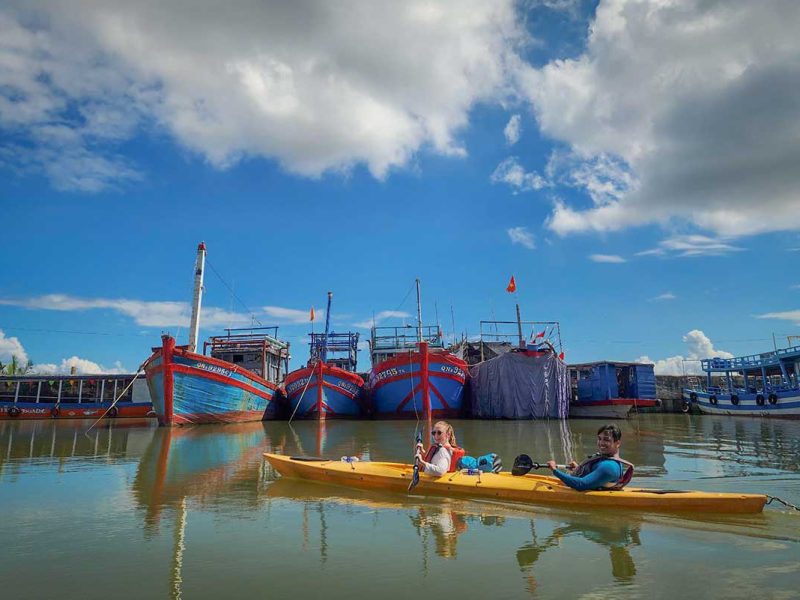 kayaking hoi an old town mangrove tour 1 Kayaking past traditional fishing boats on the Thu Bon River during the Hoi An Old Town & Mangrove Tour