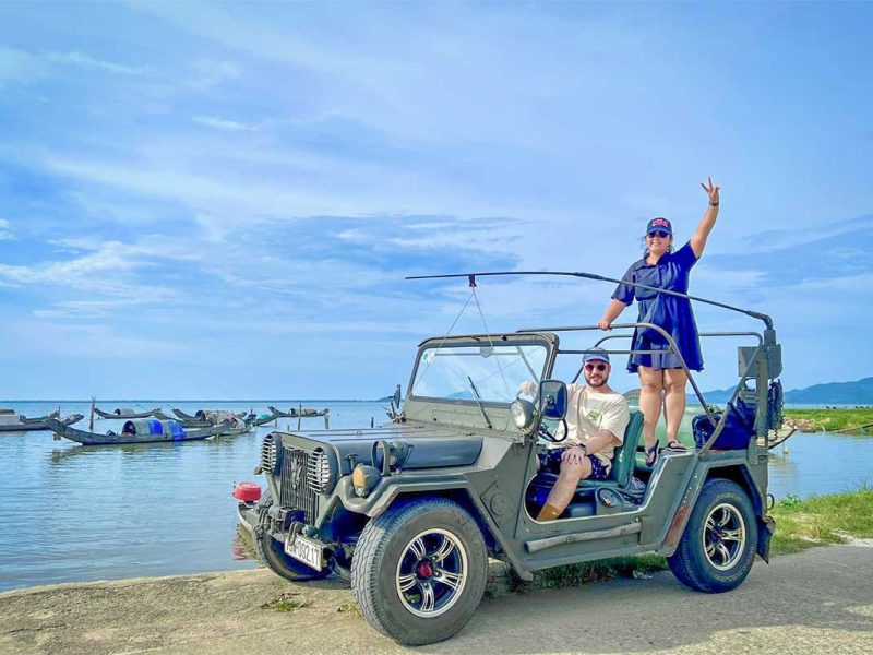 military jeep hai van pass tour hue hoi an 2 Traveler posing with a military jeep beside the fishing villages of Tam Giang Lagoon during the Hai Van Pass tour from Hue.