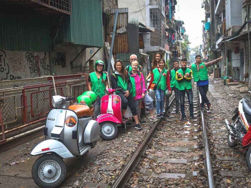 motorbike tour hanoi vespa 13 Group of travelers on Hanoi Train Street with Vespa motorbikes parked nearby during a motorbike tour