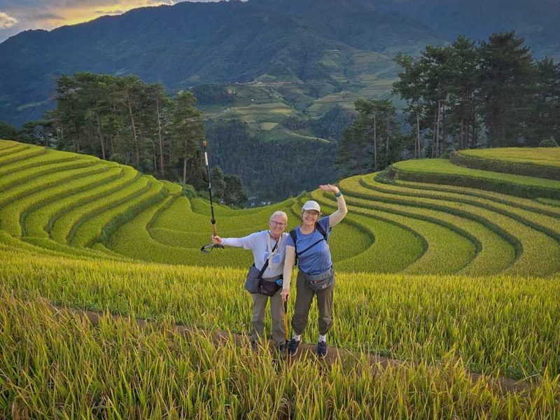 mu cang chai tour 14 Mu Cang Chai trekking tour with two travelers hiking through golden rice terraces at sunset
