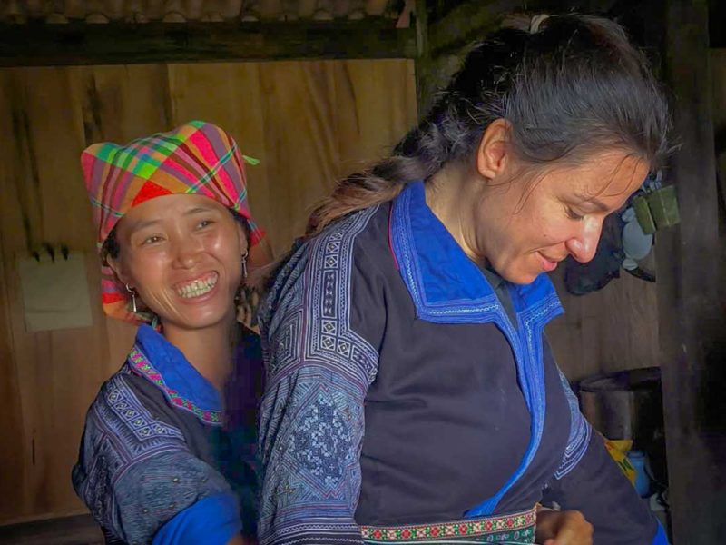 mu cang chai tour 4 Mu Cang Chai tour homestay activity with a Hmong woman helping a traveler try on traditional clothing