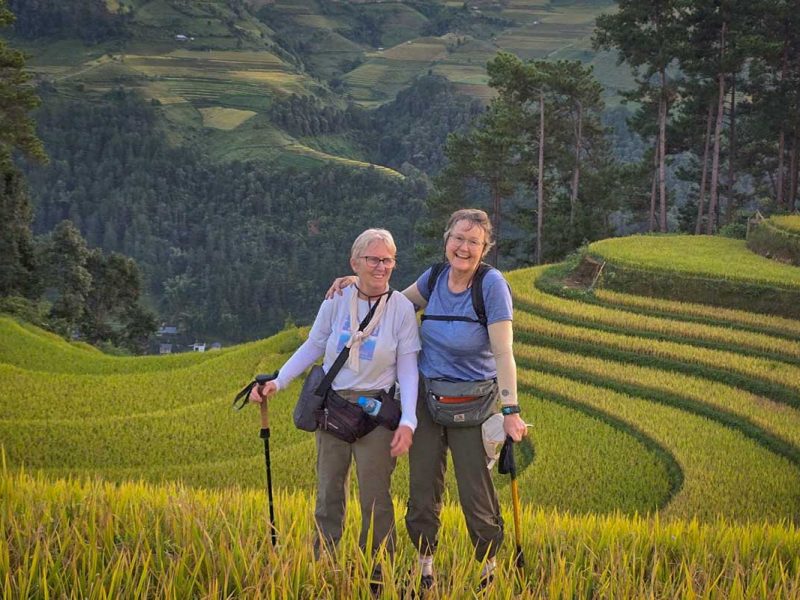 mu cang chai tour 9 Mu Cang Chai trekking tour with two hikers standing among terraced rice fields at sunset