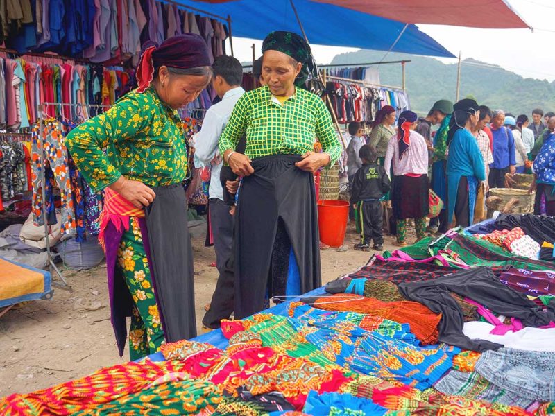 quan ba market ha giang 1 Two colorful ethnic women closely examining goods at the Quan Ba Market in Ha Giang.