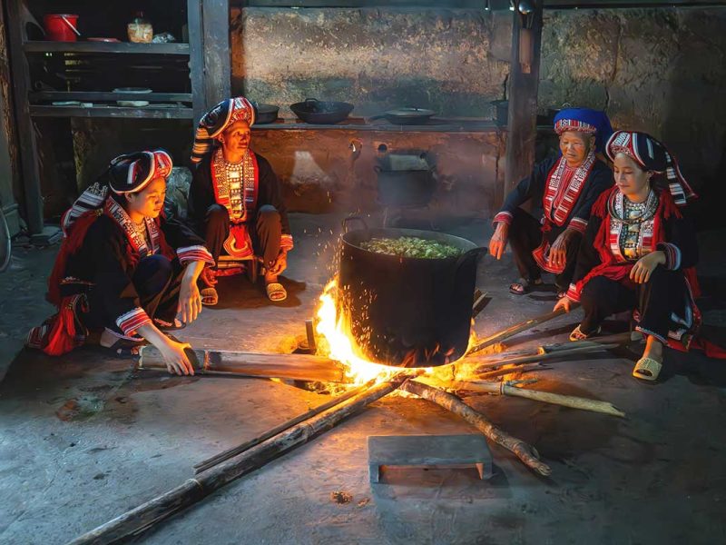 red dao hoang su phi 1 A group of Red Dao woman sitting around a cooking pot on open fire inside the house