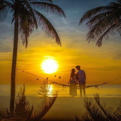 A romantic couple sitting on a hammock on the beach of Phu Quoc while watching the sunset