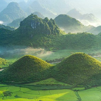 A panoramic view of the Twin Mountains in Quan Ba, Ha Giang, surrounded by lush green rice fields.