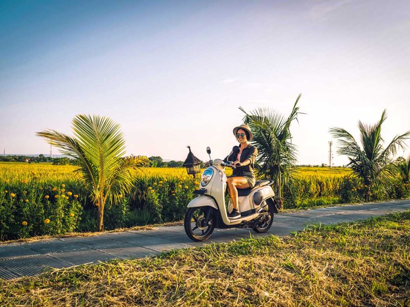 Female solo traveler riding a scooter through the picturesque rice fields of Vietnam.